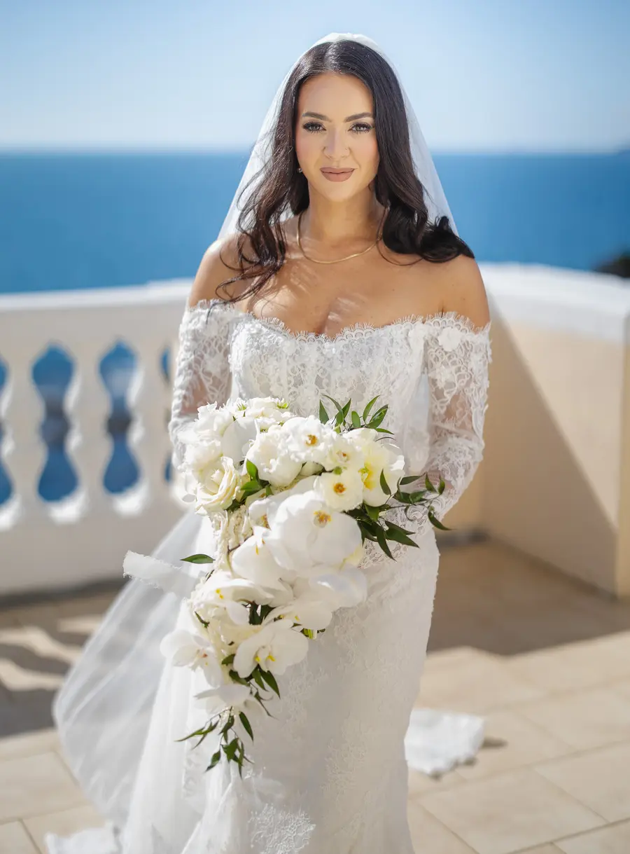 Bride Nicolette with veil and bouquet on the Villa Parisi terrace with the sea behind her