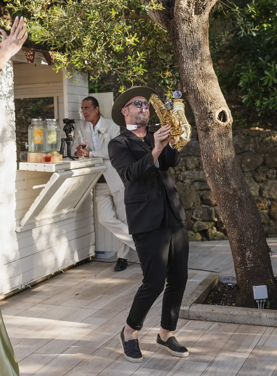Saxophonist entertaining guests during the cocktail hour under the trees at Villa Parisi