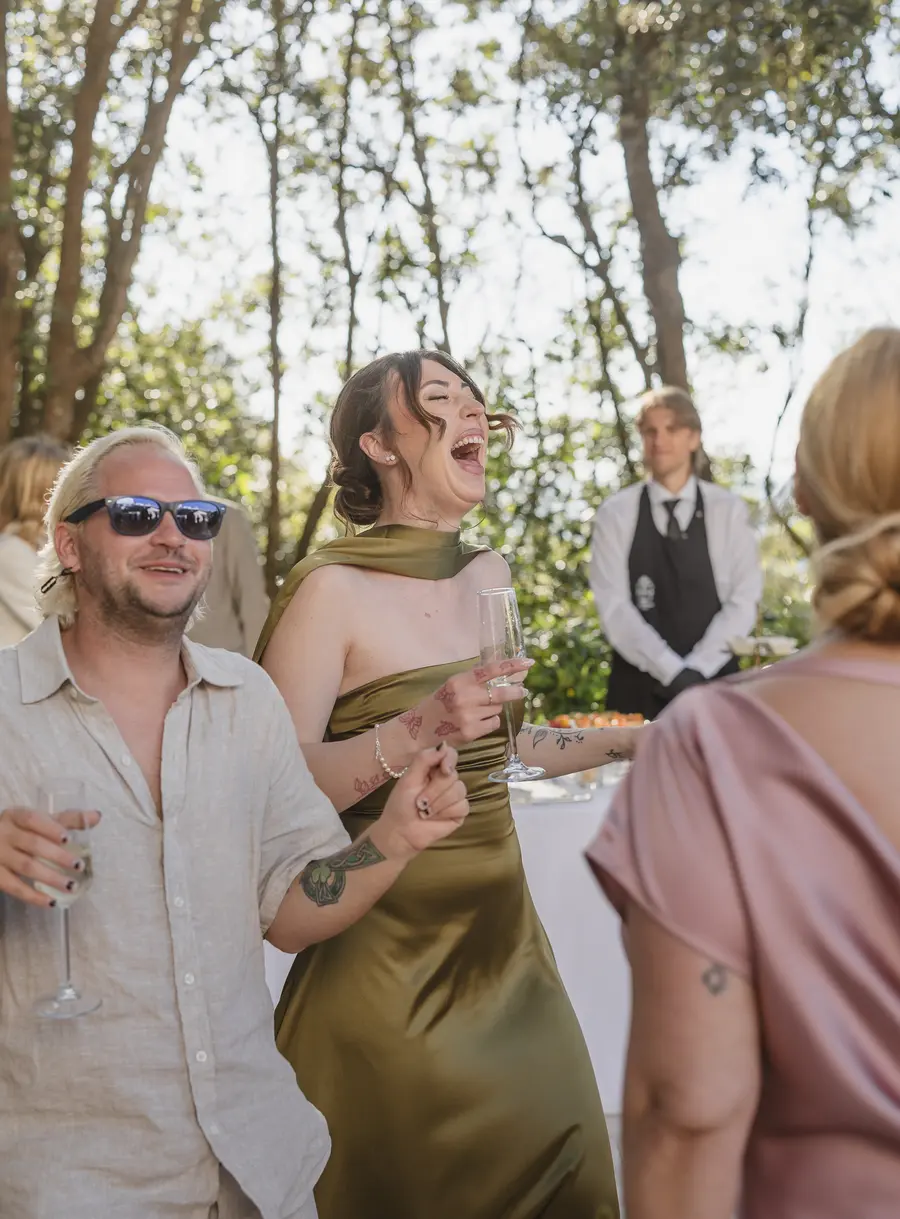 Guests laughing and toasting with champagne flutes at the outdoor cocktail hour