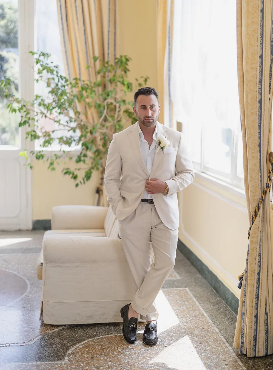 Groom portrait in a beige suit in the sunroom of Villa Parisi, Castiglioncello