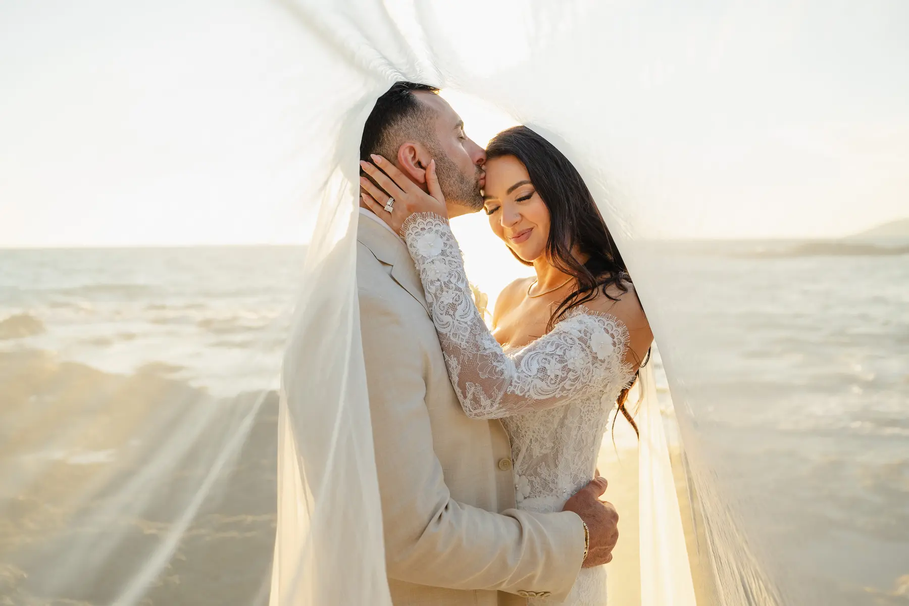 Wedding photography in Castiglioncello: couple embracing under the veil at sunset