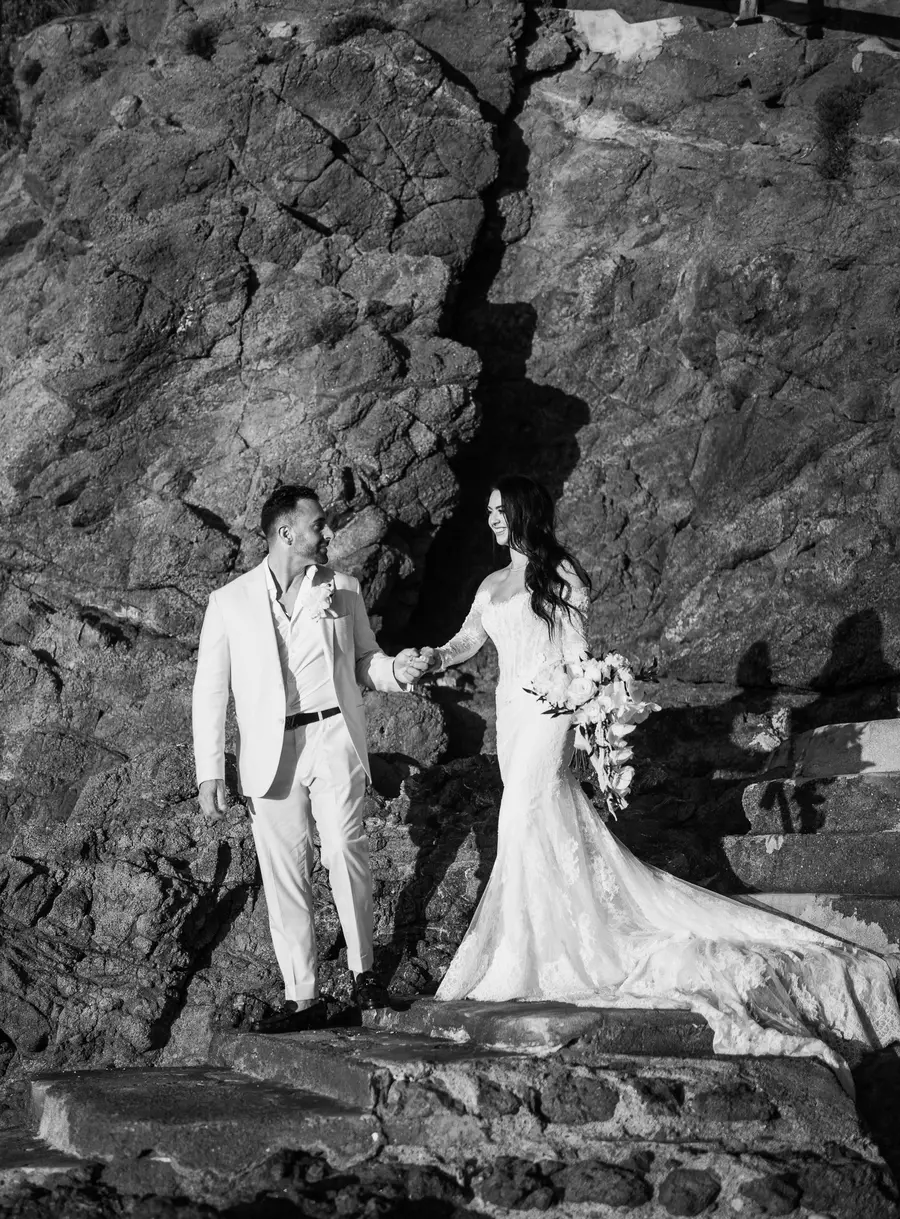 Couple holding hands among the rocks sharing a loving look, black and white