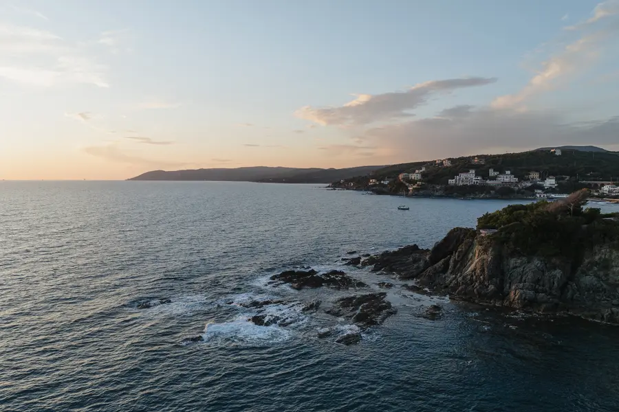 High-angle view of the Castiglioncello coast at sunset with rocks and houses on the headland