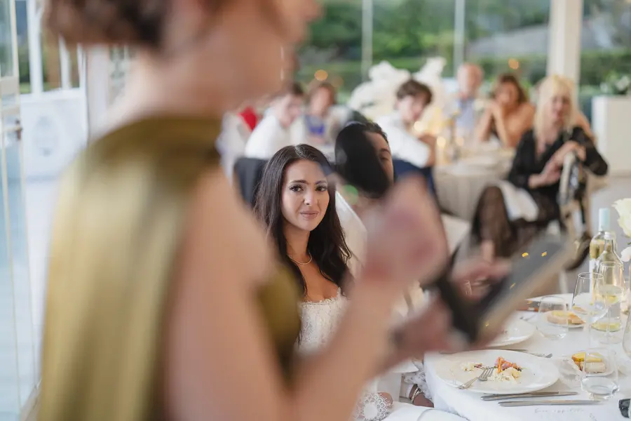 A guest giving a speech during dinner while the bride listens