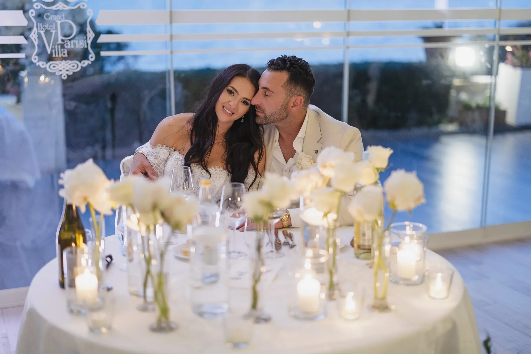 Newlyweds cuddling at their candlelit table with white roses at Villa Parisi