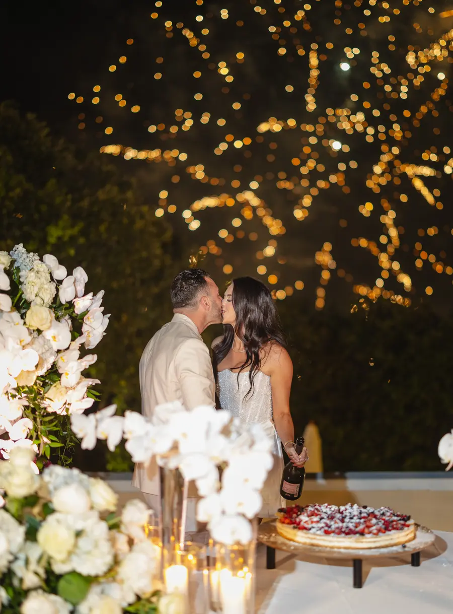 Couple kissing beside the berry cake with golden fireworks overhead
